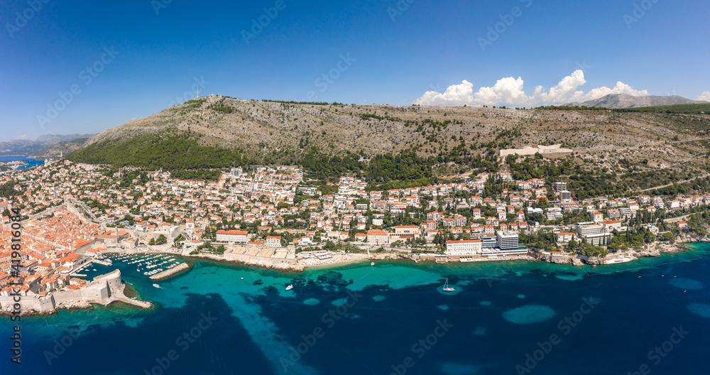 Aerial drone shot of Dubrovnik old town coastline at foot of mountain srd in Croatia summer