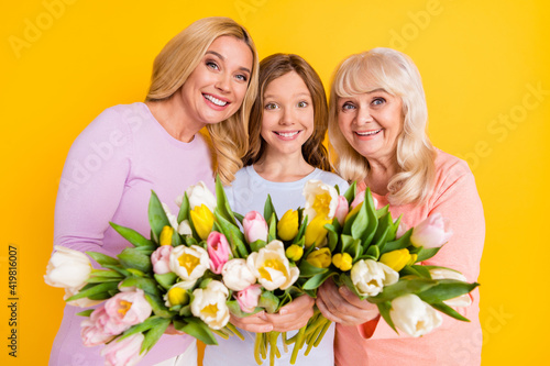 Photo of nice optimistic blond red hair grand mom daughter hold flowers wear pastel cloth isolated on yellow color background