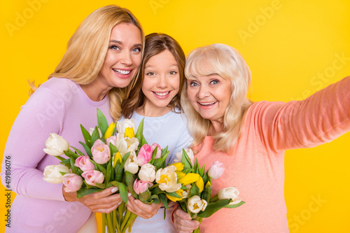 Photo of nice optimistic blond red hair grand mom daughter hold flowers do selfie wear pastel cloth isolated on yellow color background