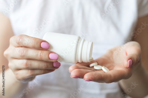 Woman pouring pills from jar into her hand, taking pills, medicine concept