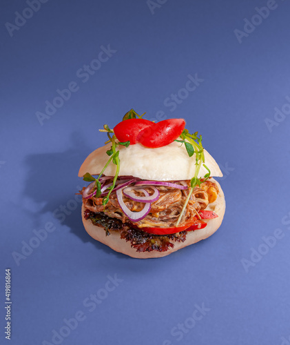Bao burger with pork and vegetables with spicy sauce. Traditional Korean cuisine. Close-up. Isolated