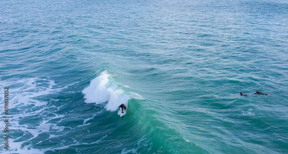 Naklejka premium Aerial drone view of surfers riding perfect Atlantic waves in the south coast of Spain, Caños de Meca near Trafalgar