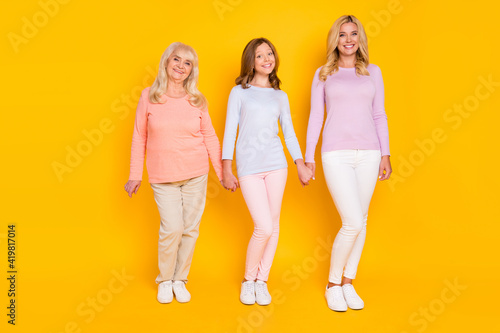 Full size photo of nice optimistic three woman grand mom daughter stand wear pastel cloth isolated on yellow color background