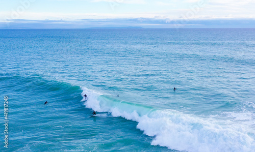 Aerial drone view of surfers riding perfect swell waves in the beach of Los Ca  os de Meca in Cadiz  South Spain