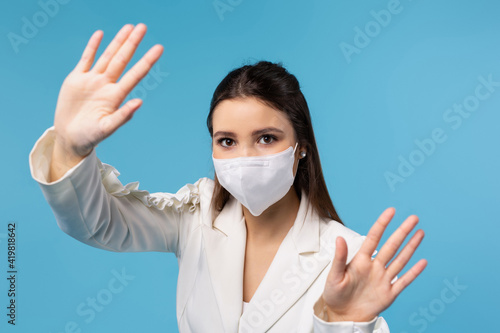 A girl office worker in a white shirt and a mask shows with her hands a stop at the camera, the end of the spread of the virus. The concept of work during quarantine.