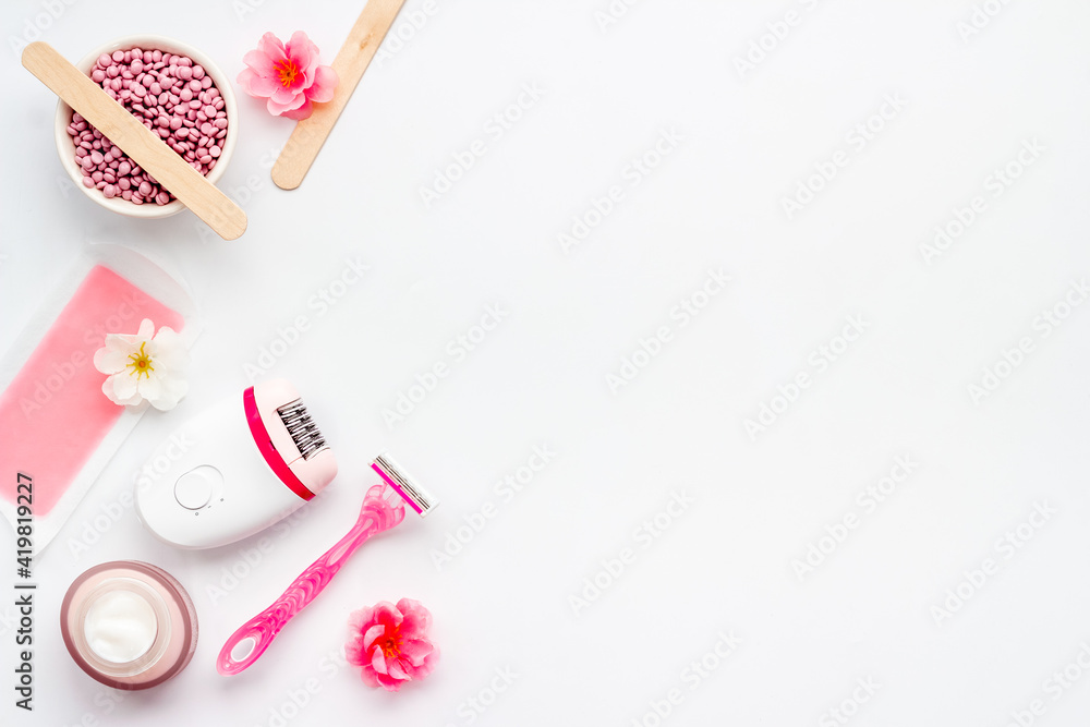 Cosmetics set for epilation with epilator and wax strips and flowers. Top view Cosmetics set for epilation with epilator and wax strips and flowers. Top view