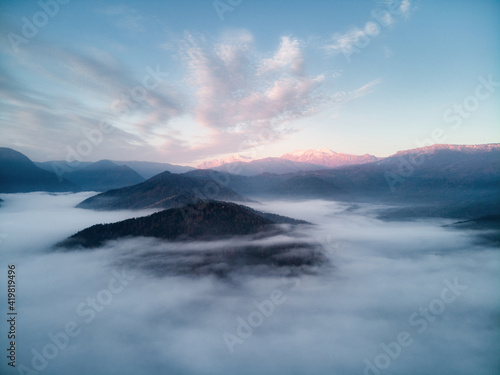 Aerial view, sea of fog and clouds illuminated by the rising sun, snow on the tops of the mountains. Russia © ASHarchenko
