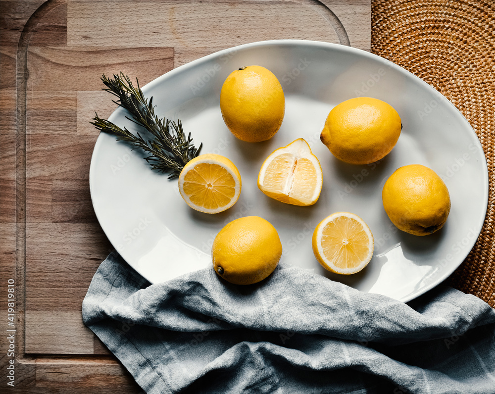 Lemons whole and cut in half, on a white plate, on wooden background Lemons whole and cut in half, on a white plate, on wooden background