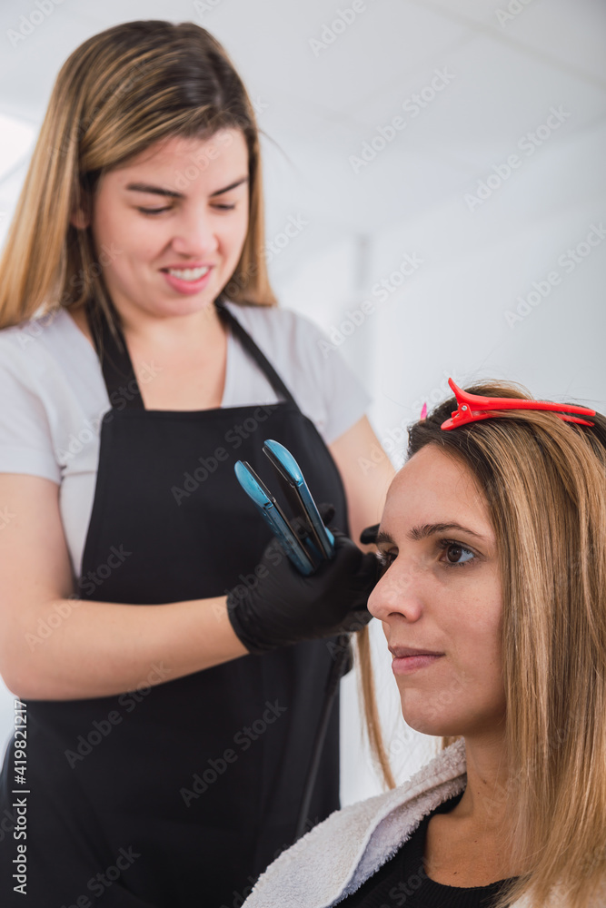 Fototapeta premium Young woman hairdresser enjoying her work.