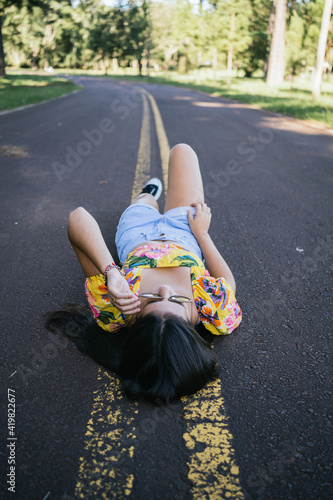 Portrait of a beautiful teenage girl lying in the road.