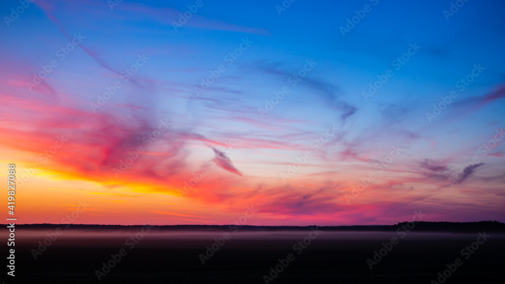incredible colorful summer sunset over the field, unusual clouds of different shapes