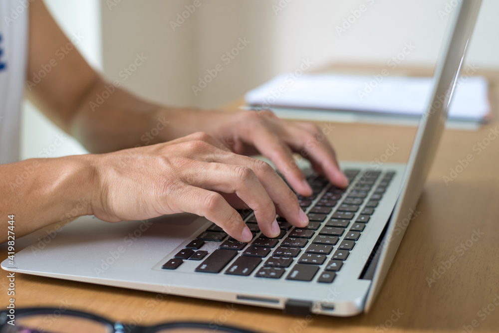 Close up image of young businessman using laptop and working online at home. He is typing on computer sitting at wooden table. Work from home concept. Close up image of young businessman using laptop and working online at home. He is typing on computer sitting at wooden table. Work from home concept.