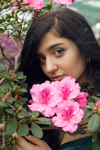 Vertical photo, dreamy girl among flowering rose bushes