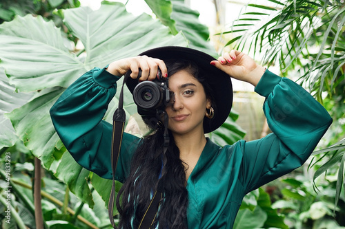 Beautiful brunette woman photographer with photo camera in tropical forest