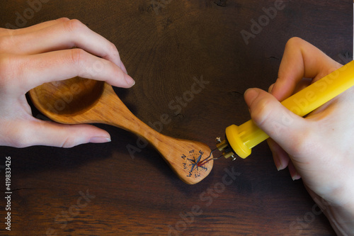 Close-up of female hands making a wind rose sign on wooden spoon.