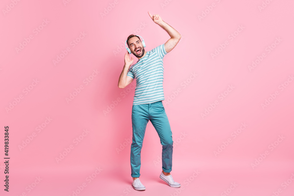 Full length body size view of nice cheerful glad guy enjoying listening modern melody having fun isolated over pink color background Full length body size view of nice cheerful glad guy enjoying listening modern melody having fun isolated over pink color background