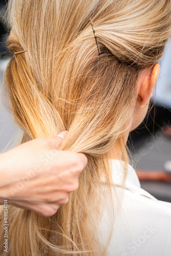 Close up of hands of female hairdresser styling hair of a blonde woman in a hair salon