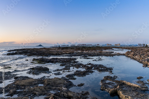 rocky tidal pools with the hotels of La Manga del Mar Menor in the background