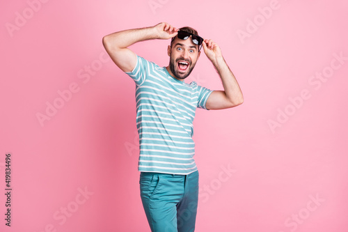 Portrait of nice cheerful lucky amazed guy wearing touching sunglasses having fun news reaction isolated over pink pastel color background