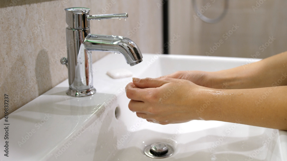 Hands of woman wash their hands in a sink with foam to wash the skin and water flows through the hands. Concept of health, cleaning and preventing germs and coronavirus from contacting hands. pandemic Hands of woman wash their hands in a sink with foam to wash the skin and water flows through the hands. Concept of health, cleaning and preventing germs and coronavirus from contacting hands. pandemic