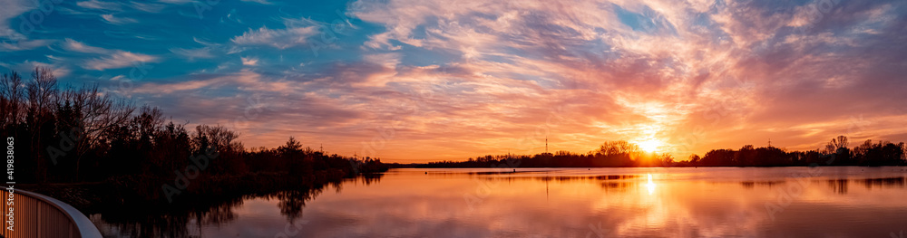 High resolution stitched panorama of a beautiful autumn or indian summer sunset with reflections near Plattling, Isar, Bavaria, Germany