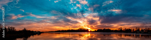 High resolution stitched panorama of a beautiful autumn or indian summer sunset with reflections near Plattling, Isar, Bavaria, Germany