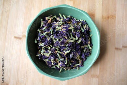 Herbal tea of purple flowers in green bowl.