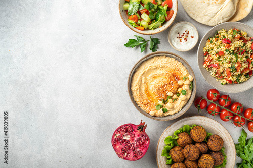 Middle eastern or arabic cuisines, falafel, hummus, tabouleh, pita and vegetables on a concrete background, view from above, copy space