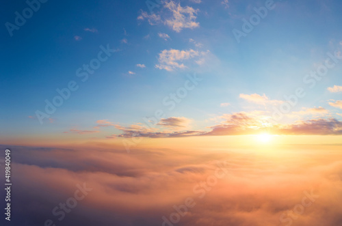 panoramic view from an airplane on a beautiful saturated sunrise above the clouds in red and orange shades © yelantsevv