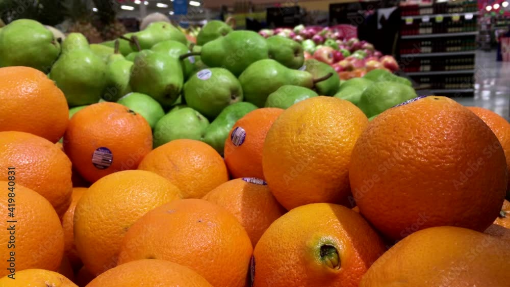Woman's hand picking orange inside Save on foods store. Woman's hand picking orange inside Save on foods store.