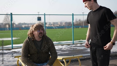 A transgender man with long hair and a beard is sitting and a bully is telling him something and a verbal altercation took place between them
