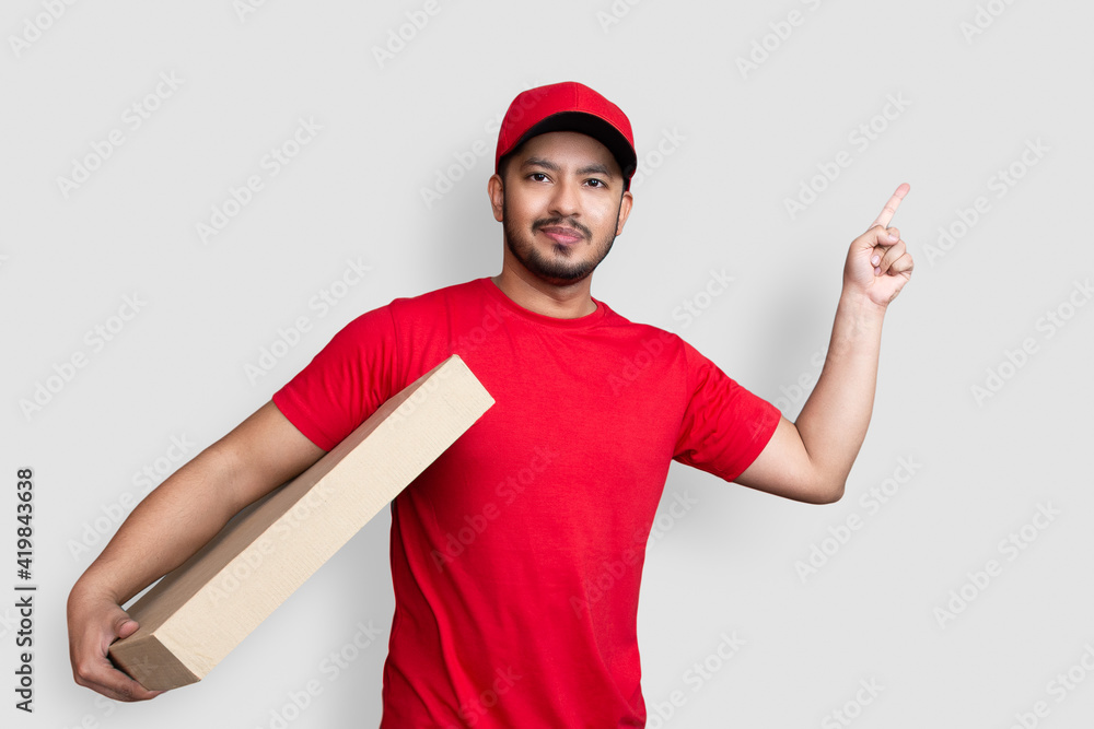 Delivery man employee in red cap blank t-shirt finger uniform hold empty cardboard box isolated on white background