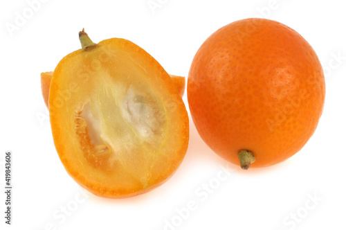 Kumquat entier et coupé en deux en gros plan sur fond blanc