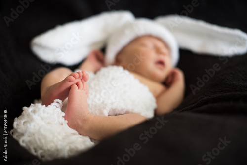 defocused newborn baby's foot in a bunny costume, close up , black background