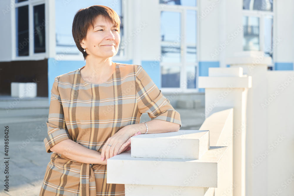 Portrait of happy caucasian adult business woman on city background, elderly lady in elegant dress Portrait of happy caucasian adult business woman on city background, elderly lady in elegant dress