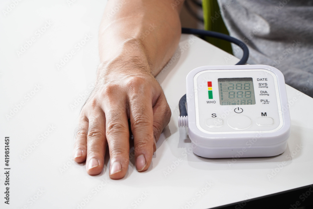 Monitoring blood pressure of patients using upper arm blood pressure monitor in the clinic examination room. Monitoring blood pressure of patients using upper arm blood pressure monitor in the clinic examination room.
