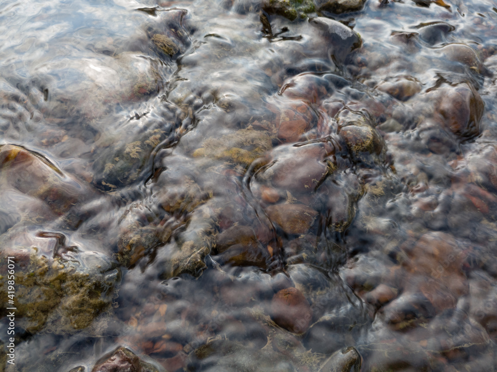 Shallow clear water flows over small stones, simple serene landscape, detail from river