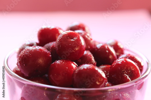 cherry in a glass on a pink red background with a place to text the view from the side close-up of the copyspace