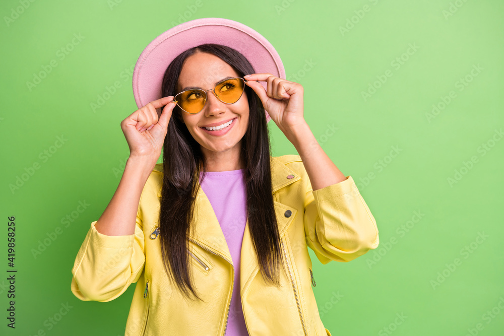 Photo portrait of curious woman touching yellow sunglass looking at copyspace isolated on bright green color background Photo portrait of curious woman touching yellow sunglass looking at copyspace isolated on bright green color background