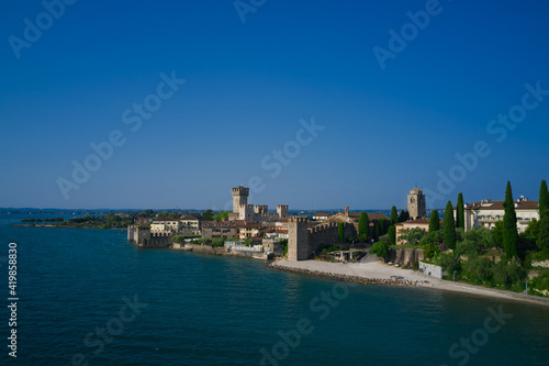 View by Drone. Rocca Scaligera Castle in Sirmione. Aerial view on Sirmione sul Garda. Italy, Lombardy. Amazing view to the old bridge and harbor of Sirmione.