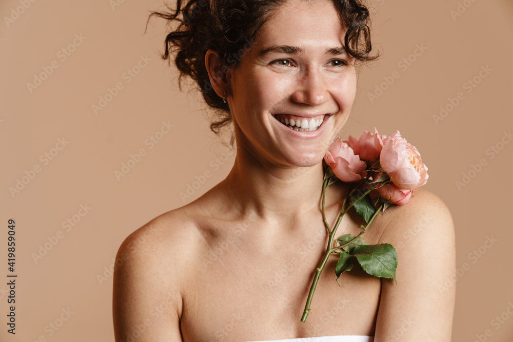 Half-naked curly woman laughing while posing with pink flower Half-naked curly woman laughing while posing with pink flower
