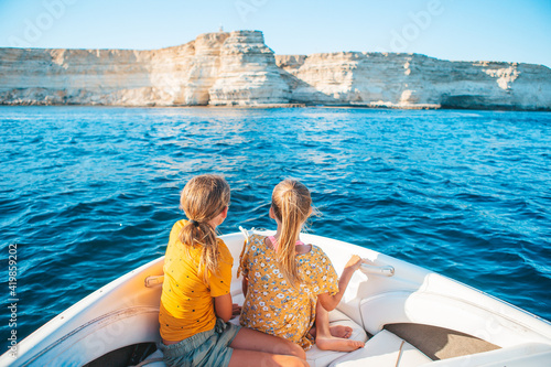 Little girls sailing on boat in clear open sea photo