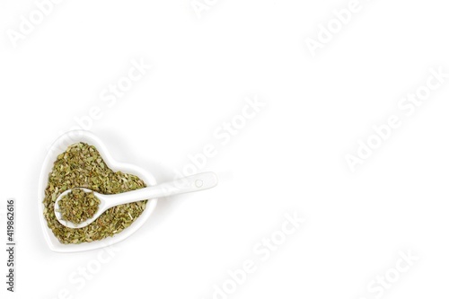 Dried herbs or spices in a bowl with spoon on a white background 