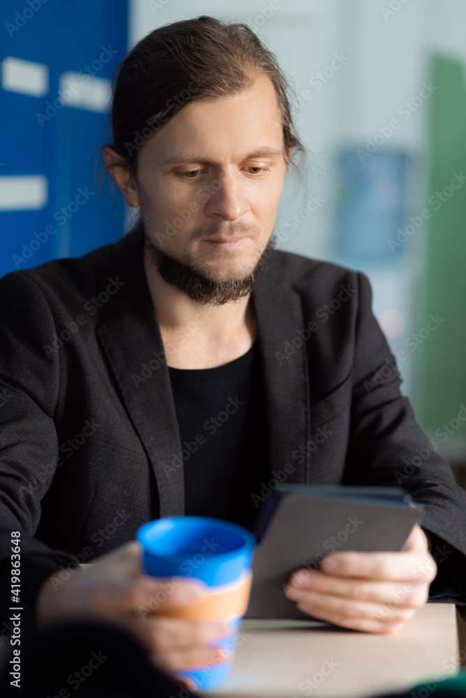 Businessman sitting at cafe reading email on his digital tablet while having coffee Businessman sitting at cafe reading email on his digital tablet while having coffee