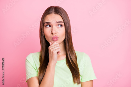 Photo of unsure sad young girl dressed green t-shirt arm chin looking empty space isolated pastel pink color background