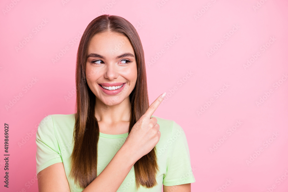 Photo of dreamy shiny young lady wear green t-shirt looking pointing empty space isolated pastel pink color background Photo of dreamy shiny young lady wear green t-shirt looking pointing empty space isolated pastel pink color background
