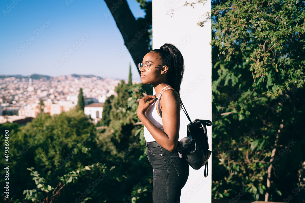 Side view of young contemplative female tourist with travel backpack  thinking about city sightseeing, pensive African American hipster girl with  dark skin thoughtful looking away during sunny day Stock Photo | Adobe