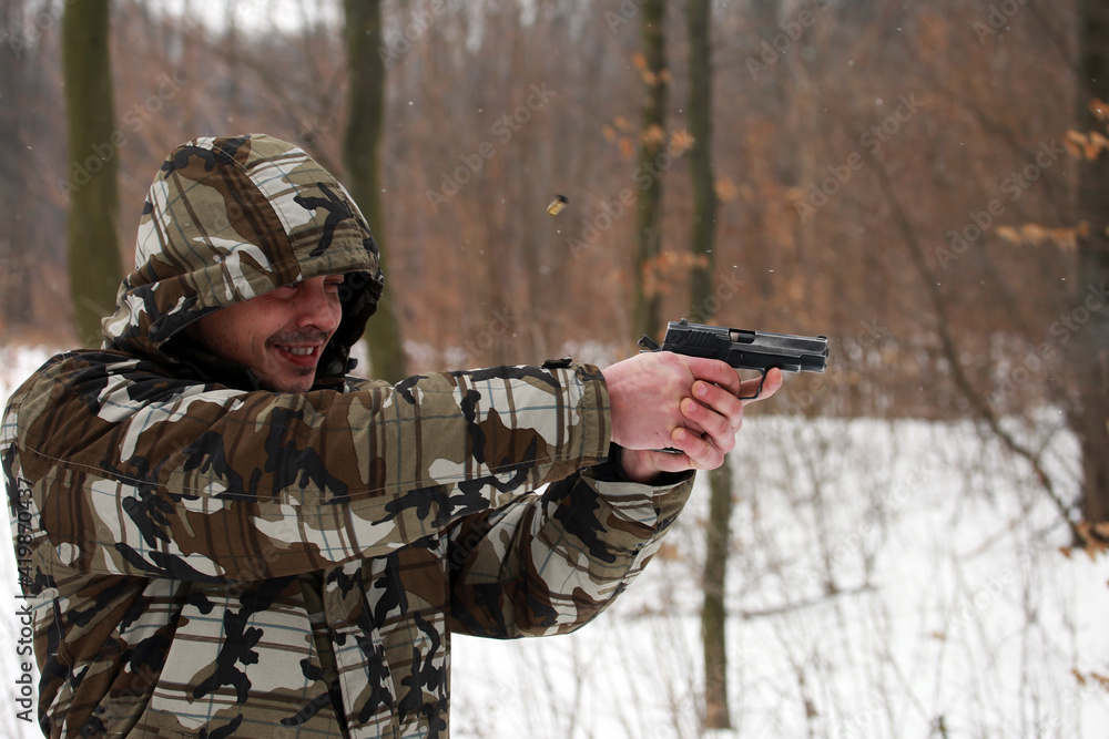 Soldier shooting with a pistol in the forest in winter