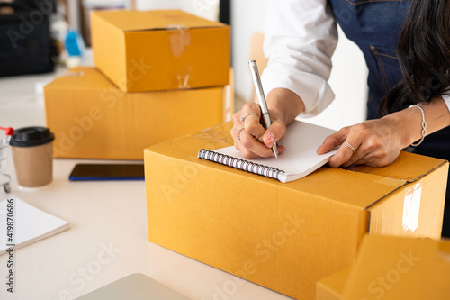 Starting small businesses SME owners female entrepreneurs Write the address on receipt box and check online orders to prepare to pack the boxes, sell to customers, sme business ideas online. © crizzystudio