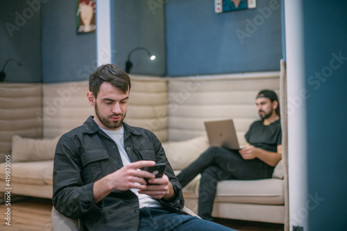 Men work with a smartphone and laptop in the office